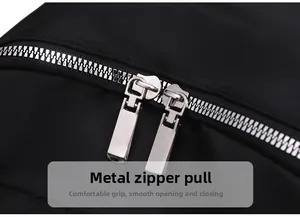 Detail of durable metal dual zippers on smooth black nylon backpack with easy-grip design