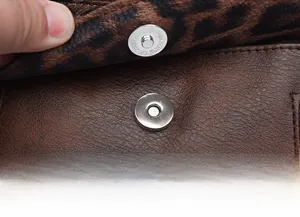 Close-up of magnetic snap closure on brown leather backpack with leopard print lining