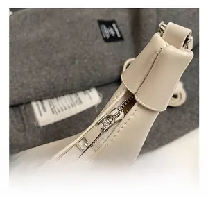 Détail de la fermeture éclair argentée et des coutures sur un sac à main en cuir beige