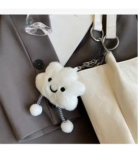 Close-up of white plush cloud charm with embroidered smile on a white leather tote bag