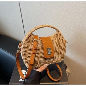 Detail of woven straw handbag featuring brown leather flap and silver twist lock closure