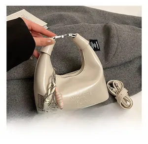 Détail du sac hobo crème avec cordon tressé et pendentif de raquette de tennis