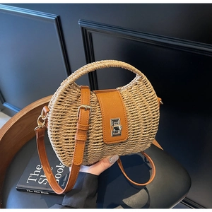 Detailed view of straw woven crossbody bag with brown leather flap and silver metal turn-lock