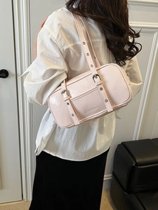 Pink Boston shoulder bag with decorative buckle straps shown on model in indoor setting
