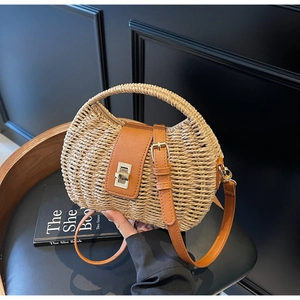 Detail of woven straw bag showing the brown leather flap and golden twist-lock closure