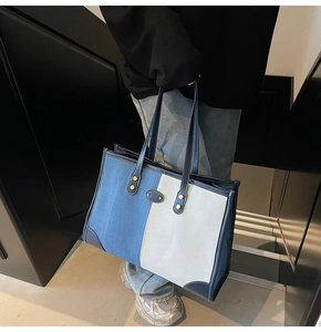 Detail of blue and white denim tote bag with navy leather handles and gold metal rivets