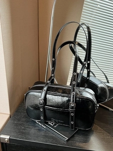 Glossy black pleated Boston bag with eyelet straps and shiny patent leather texture