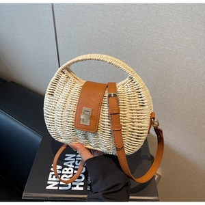 Detail of hand-woven straw bag with brown leather flap and adjustable crossbody strap