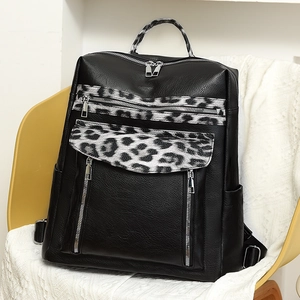 Close-up of a leopard print backpack with multiple zippers and black leather textures