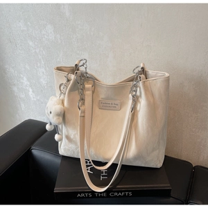 Detail of off-white tote bag with silver chain handle and plush cloud charm accessory