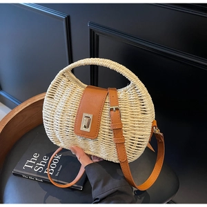 Detail of hand-woven straw bag with premium brown leather strap and metal buckle closure