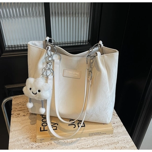 Detail of off-white textured tote bag with silver chain strap and plush cloud charm