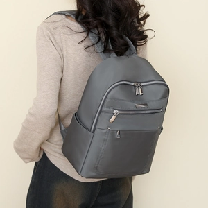 Close-up of high-density waterproof nylon fabric and silver metal zippers on grey backpack