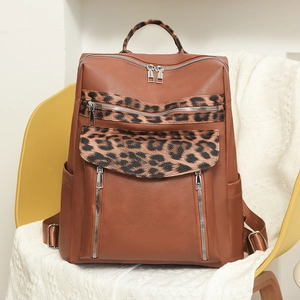 Detail view of brown faux leather backpack featuring leopard print accents and silver zippers