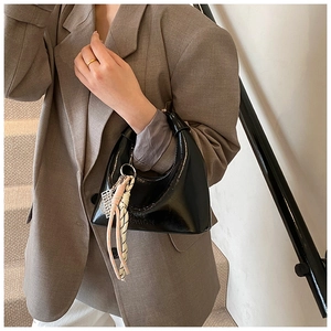 Détail d'un sac hobo noir avec lettrage embossé et ornement en corde tressée rose