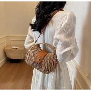 Detail of hand-woven straw bag with premium brown leather strap and metal buckle closure