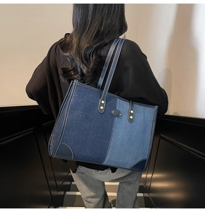 Detail of color-block denim tote bag featuring contrast stitching and metal rivets