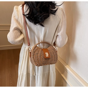 Detail of hand-woven straw bag with dark brown PU leather flap and gold metal lock closure