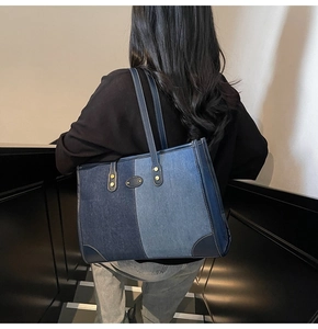 Detail of a large denim tote bag featuring blue patchwork design and gold rivet accents