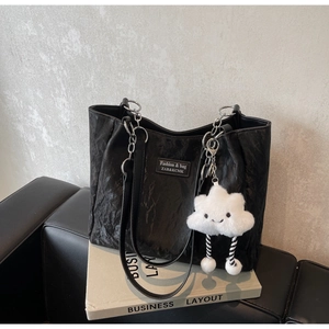 Detail of black pleated tote bag with silver chain strap and cute cloud charm on books