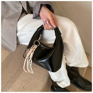 Détail du sac hobo noir verni avec breloque en corde tressée et lettrage embossé sur cuir