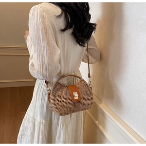 Detail of woven straw crossbody bag with brown leather flap and metal turn-lock closure