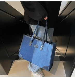 Detail of blue denim patchwork tote bag with gold rivets and leather patch on steps