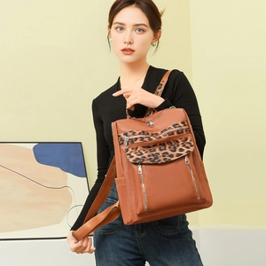 Leopard print details on brown leather backpack with multiple silver zippers and fabric straps