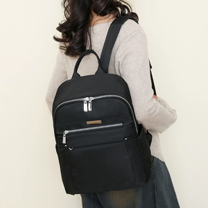 Detail of waterproof black nylon backpack with silver zippers and golden metal plaque