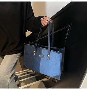 Close-up of contrast stitching on denim tote bag with blue leather trim and rivets