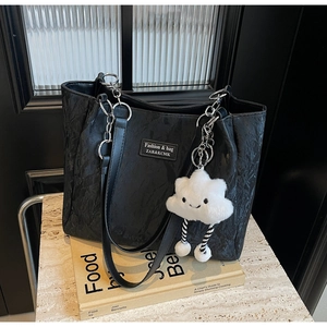 Close-up of black pleated tote bag with silver chain strap and white cloud charm