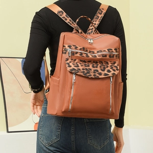 Detail view of leopard print backpack with brown leather and silver zipper on female model