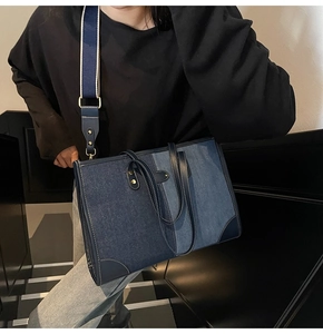 Detailed view of dual-tone denim tote bag with leather patches and wide shoulder strap