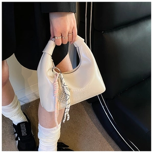 Détail d'un sac à main en cuir verni blanc crème avec relief et charme tressé