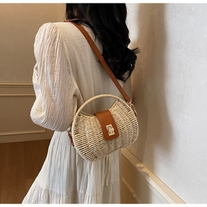 Detail of woven straw crossbody bag featuring brown leather flap and golden metal clasp