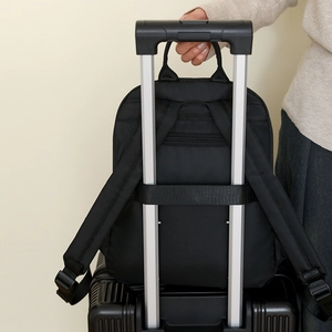 Detail showing the trolley sleeve of a black nylon backpack attached to luggage handle