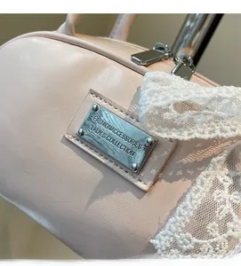 Detail of light pink shoulder bag with silver metal plaque and delicate lace bow