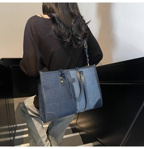 Detail of denim patchwork tote bag showing contrast stitching and leather trim accents