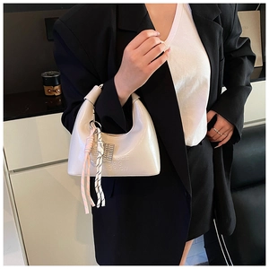 Détail du sac hobo en cuir verni beige avec breloque raquette de tennis et gaufrage OSHE