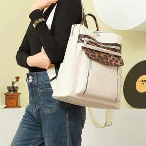 Detail of beige leopard print backpack showing PU leather texture and zip compartments