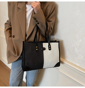 Detail of color-block tote bag with gold rivets and leather trim worn on shoulder