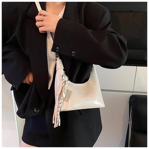Détail d'un sac hobo blanc crème avec pompon latéral et pendentif en maille métal