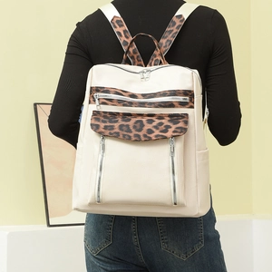 Detail of stylish cream leather backpack with leopard print straps and silver zippers
