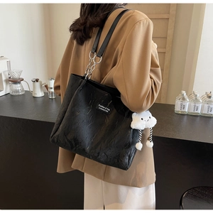 Detail of black wrinkled tote bag with silver chain and white plush cloud charm