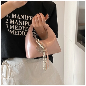 Vue détaillée du sac à main en cuir verni rose avec poignée nouée et breloque métallique