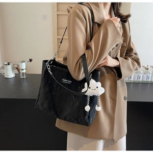 Detail of black pleated tote bag with silver chain strap and white cloud charm