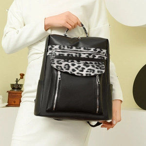 Detail of black pebbled leather backpack featuring stylish leopard print accents and zippers