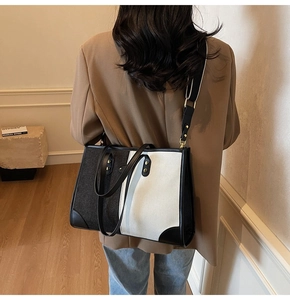 Detail of contrast color tote bag with canvas texture, leather corners, and gold hardware