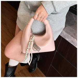 Détail du sac à main rose en cuir avec fermeture tressée et pendentif métallique chic