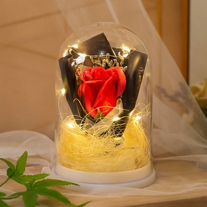 Preserved red rose in glass dome with warm LED fairy lights on white base